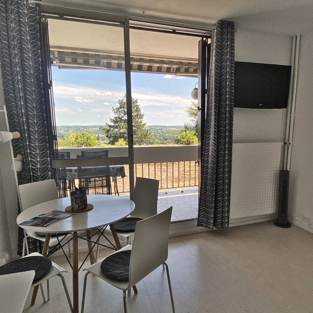 La pièce de vie avec vue sur le balcon, table pour le repas et télévision
